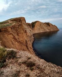 Scenic view of mountain by sea against sky