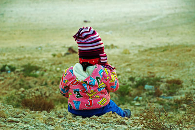 Rear view of boy sitting on field