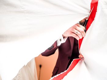 Midsection of woman holding umbrella standing against white wall