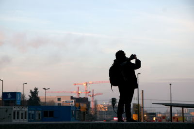 Man photographing against sky during sunset