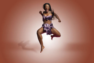 Portrait of young woman dancing against colored background