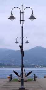 Street light by sea against sky