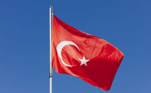 Low angle view of turkish flag against clear blue sky