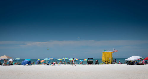 People on beach against blue sky