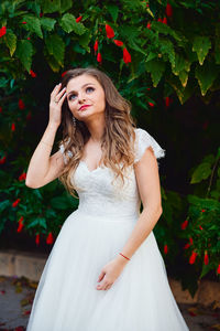 Portrait of beautiful young woman standing against white