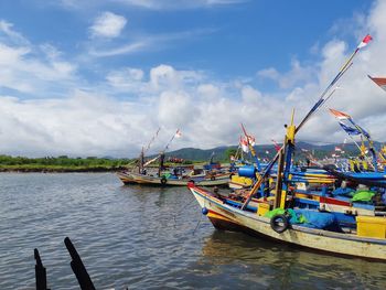 Fishing boats moored in sea against sky