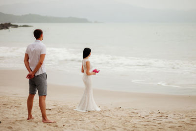 Rear view of couple standing at beach