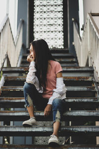 Thoughtful woman sitting on staircase