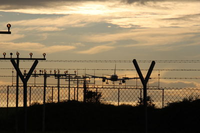 Silhouette fence by sea against sky during sunset