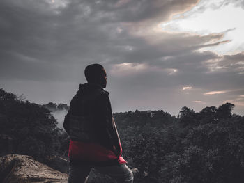 Rear view of man standing on mountain against sky