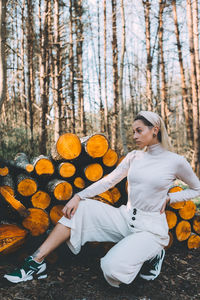 Young woman sitting on log in forest