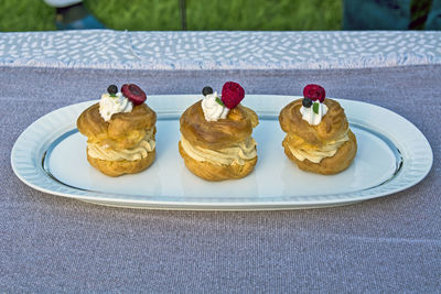 Three princess donuts on a plate with sweet fruit decorations on them.