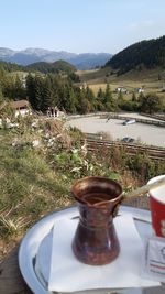 Drinking glass on table by mountains against sky
