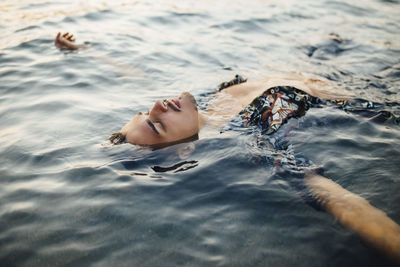 Young man with eyes closed wearing unbuttoned shirt while floating in water