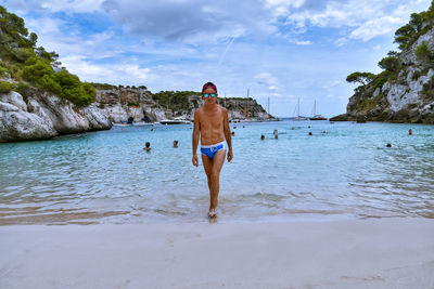 Rear view of shirtless man walking on beach