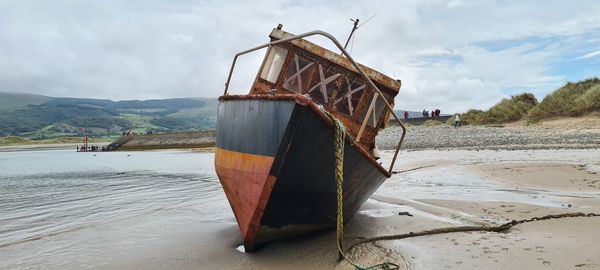 Boat moored on beach against sky