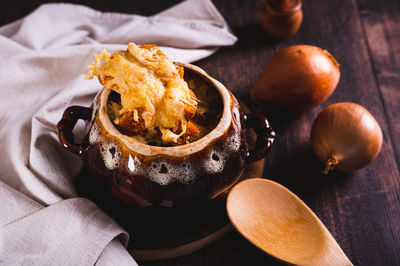 Homemade onion soup with cheese croutons in a pot on the table