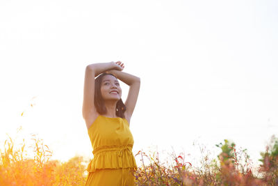 Young woman standing against plants against clear sky