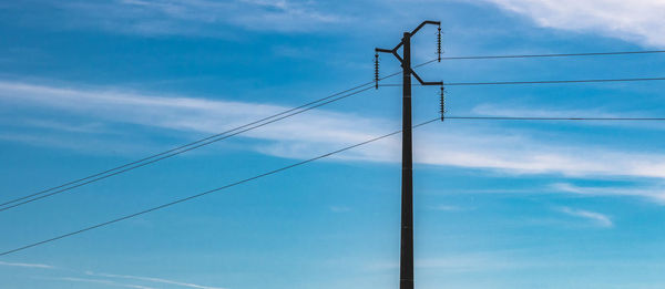 Low angle view of power lines against blue sky