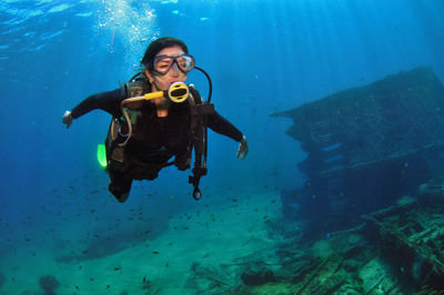 A woman doing scuba diving near a shipwreck