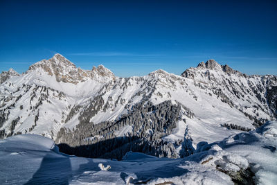 Scenic view of snowcapped mountains against clear blue sky