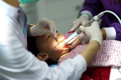 Midsection of dentists examining patient mouth in hospital