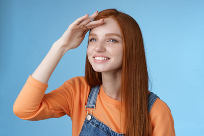 Portrait of smiling young woman against blue background