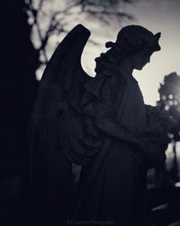 Close-up of angel statue in cemetery against sky