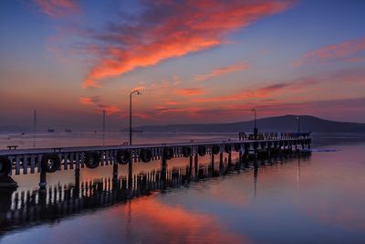 Pier on sea against sunset sky