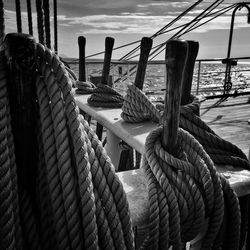 Close-up of rope tied to bollard by sea against sky