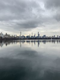 Scenic view of lake by buildings against sky