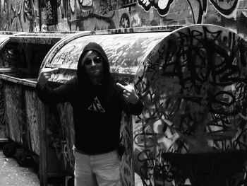 Portrait of young woman standing against graffiti wall