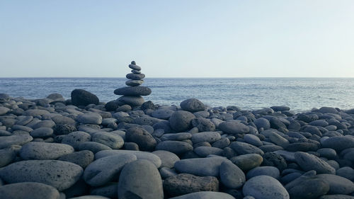 Stack of stones on beach against clear sky