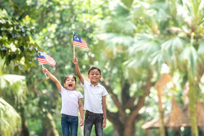 Father and girl holding flag against blurred background