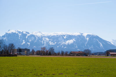 Scenic view of field by mountains against clear sky