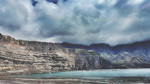 Sea by mountain against sky