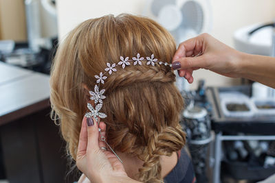 Cropped hands of beautician putting tiara on bride hair at spa