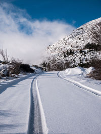 Road amidst snow covered trees against sky