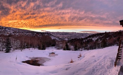 Scenic view of snow covered mountains against sky at sunset