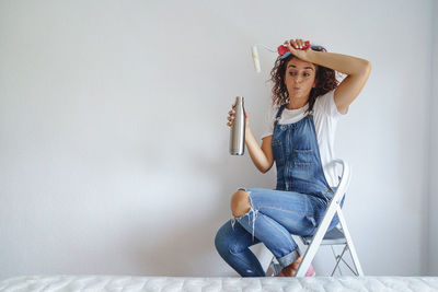 Young woman sitting against wall at home