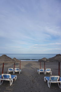 Chairs on beach against sky