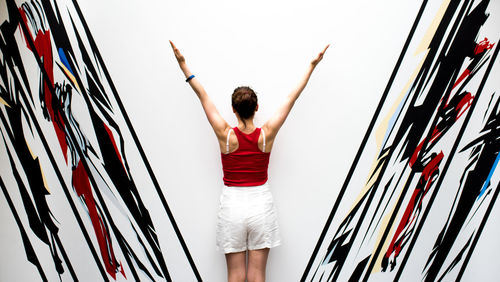 Rear view of young woman standing against red background