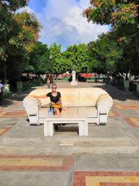 Man sitting in park against sky in city