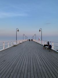 People on pier by sea against sky