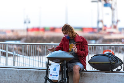 Woman sitting on railing against boat