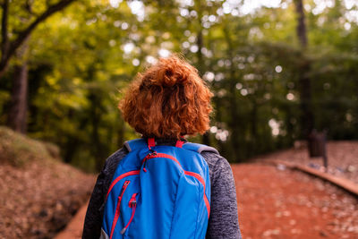 Rear view of woman standing against trees