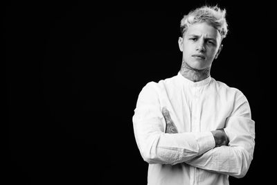 Portrait of man standing against black background