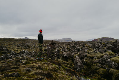 Man walking around lava filed covered in green moss in iceland