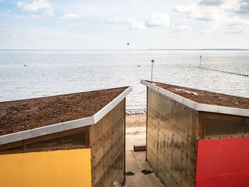 Beach huts with living roofs, and red and yellow panels on the beach at shoeburyness