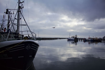 Boats in sea against cloudy sky